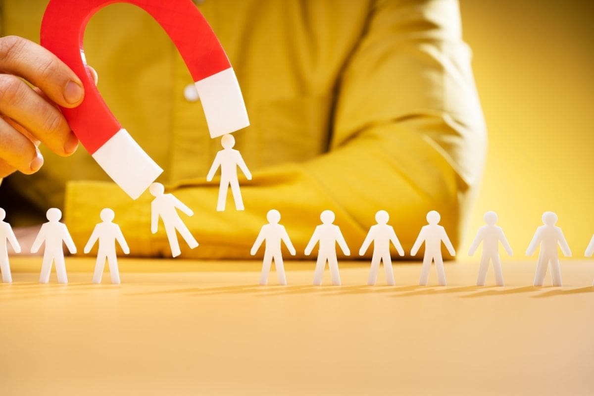 Illustration einer Magnetfigur, die stilisierte Menschen anzieht, Symbol für die Anziehungsphase im Inbound-Marketing