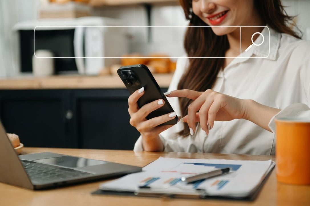 Mulher sorrindo enquanto realiza uma busca no celular em uma barra de pesquisa digital, ilustrando como o comportamento de busca está migrando para assistentes de IA generativa como ChatGPT e Gemini.