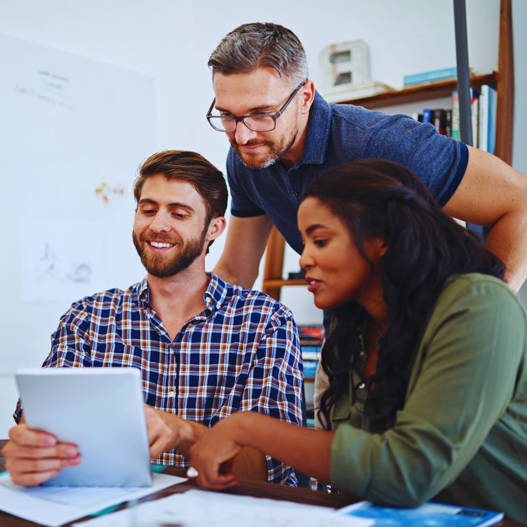 Beraterin unterstützt Kundin im persönlichen Gespräch, während ein Marketingteam im Hintergrund Daten analysiert – transparente Kommunikation, messbare KPIs und individueller Service für nachhaltigen Geschäftserfolg.