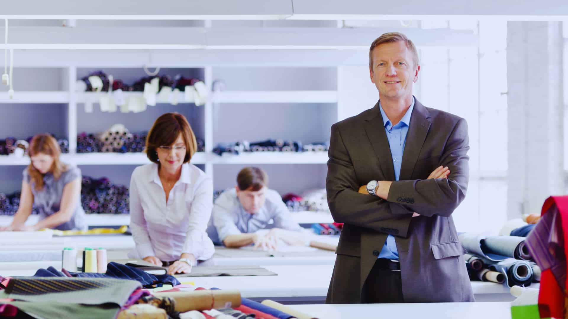 Textile company owner and his team working in the background — WPN provides content marketing for the fashion and manufacturing industries.