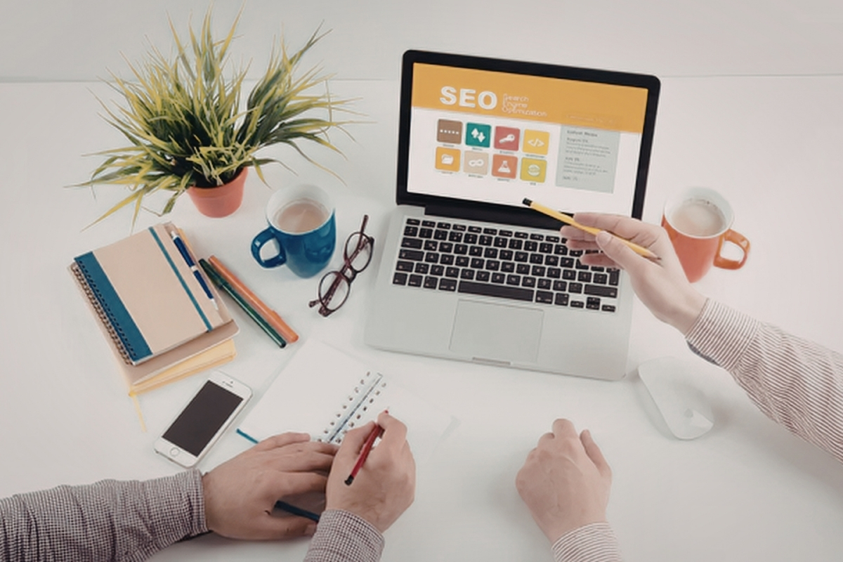 Mãos digitando em notebook com página de SEO aberta, representando produção de conteúdo estratégico para blog